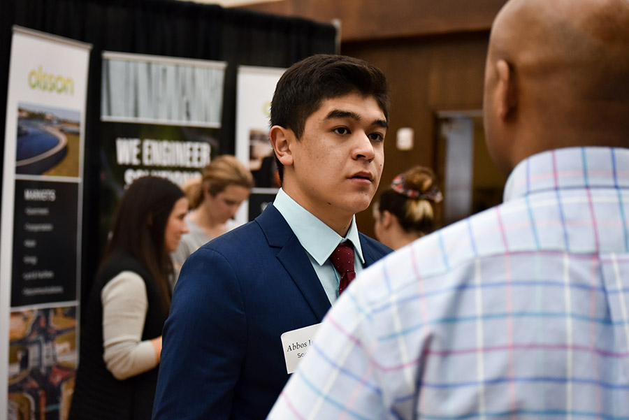 Male student at a career fair talking to a potential employer.