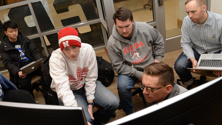 Robert Hutchinson (second from left) and mentor Michael Peterson (foreground) discuss final details for team presentations.