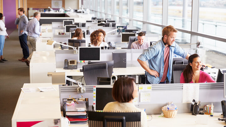 Casually dressed colleagues talking in an open plan office