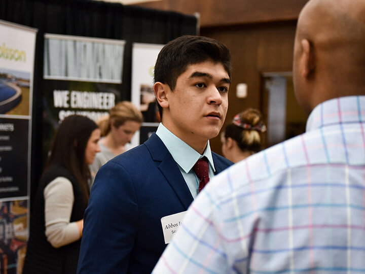 Male student at a career fair talking to a potential employer.