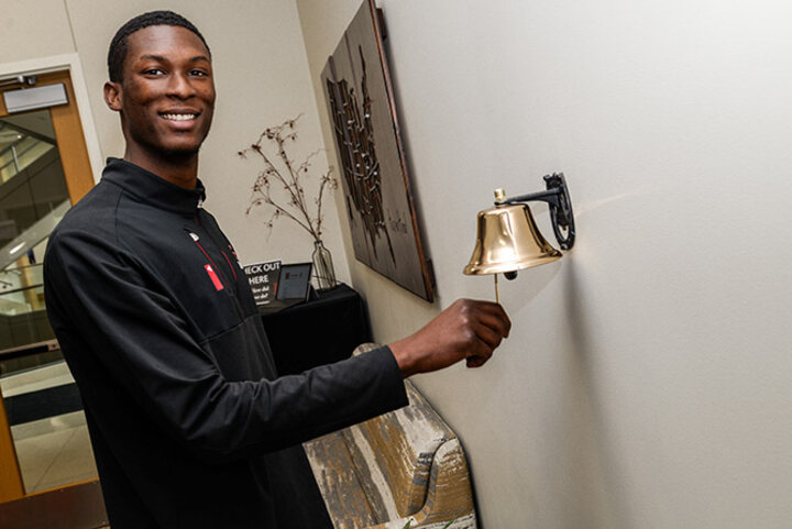 Phillips proudly rings the Success Bell after securing a job at Holland Basham Architects.