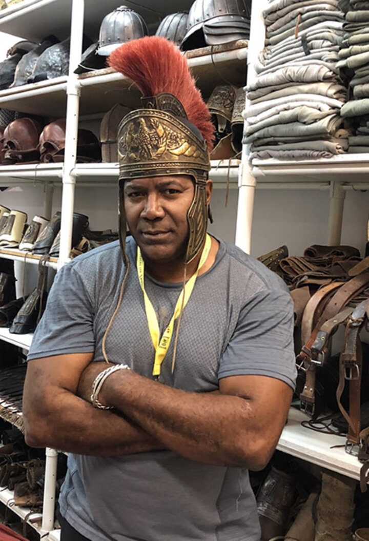 Williams dons his superhero costume for the day at a film studio, soaking in his love for imaginative content creation.